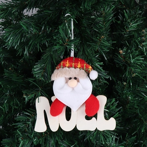 Dettaglio di Babbo Natale con targa Noel in legno appesa a un fitto albero di Natale verde