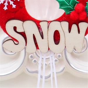 Detailopname van een rode pluche kersthanger met houten SNOW letters en groene decoraties