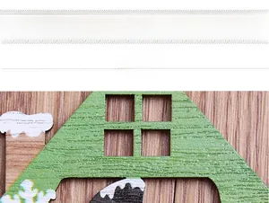 Detail of wooden Christmas ornament showing green painted roof and laser-cut window patterns