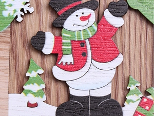 Close-up of laser-cut wooden Christmas ornaments with snowman and tree painted details