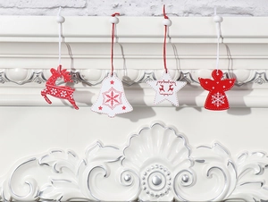Close-up of four red and white wooden Christmas ornaments hanging on a white fireplace