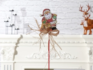 Detail eines Weihnachtssteckers aus Holz mit Bastschleife und rotem Stab für Deko