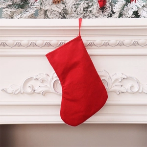 Classic red Christmas stocking hung on fireplace with festive pine needle decorations