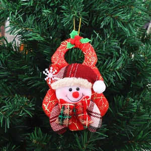 Close-up of a festive plush snowman ornament with red and gold fabric on a green tree