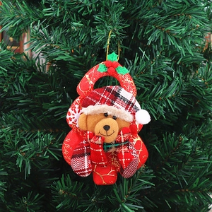 Detail of Christmas tree ornament with plush brown bear and festive holly leaves on red pouch
