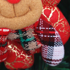 Close-up of reindeer plush ornament with Merry Christmas embroidery on red fabric