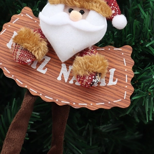 Plush Santa Claus hanging ornament with Feliz Natal wooden sign on Christmas tree