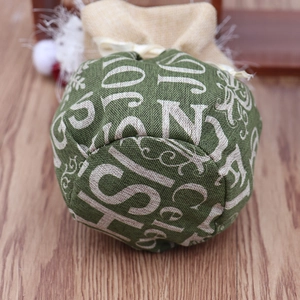 Détail macro du sac cadeau en lin vert avec imprimé festif JOY NOEL et cordelette en jute