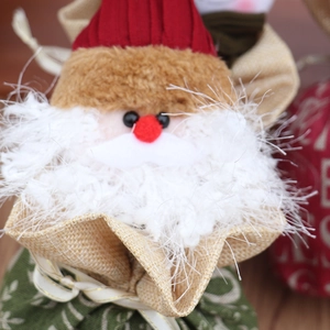 Détail d'un sac cadeau Père Noël avec bonnet tricoté et barbe en fausse fourrure blanche