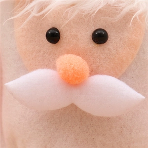 Detailed close-up of Santa Claus plush ornament with fuzzy white beard and felt textures