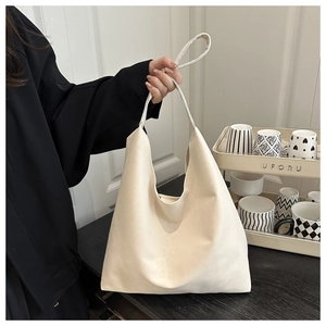 Close-up of a cream-colored leather tote bag with a soft texture and wide shoulder strap