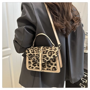 Detail of leopard print crossbody bag with gold buckle and beige leather trim texture