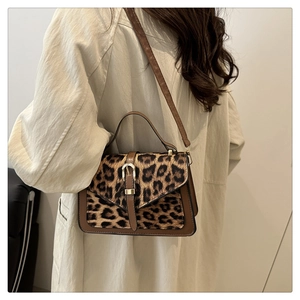 Detail of trendy leopard print handbag with brown leather trim and metal clasp closure