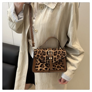 Detail view of leopard print crossbody bag featuring gold buckle and brown leather trim