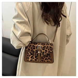 Model wearing leopard print handbag with brown leather trim and golden metal clasp