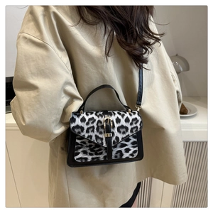 Close-up of leopard print flap and golden metal buckle on black crossbody bag