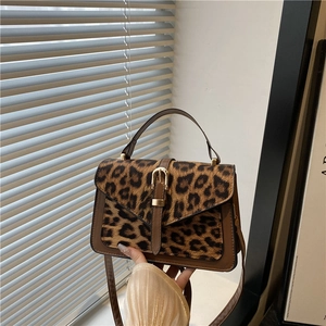 Leopard print crossbody bag with brown leather trim and golden buckle closure
