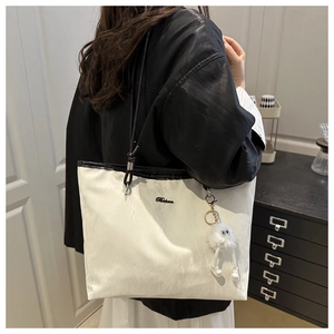 Détail du grand sac cabas blanc à texture plissée, anses noires et pendentif peluche