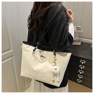 Détail du sac cabas blanc cassé avec anses noires et porte-clé peluche mignon