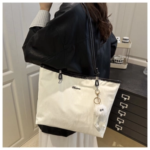 Détail du grand sac cabas crème avec anses noires et pendentif en peluche amusant
