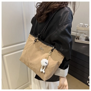 Détail d'un sac cabas kaki avec texture plissée et pendentif en peluche blanche douce