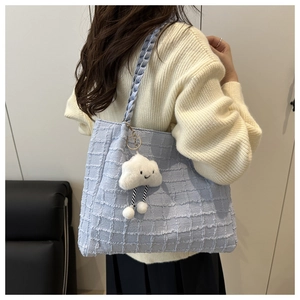 Détail du cabas en tweed bleu clair avec bandoulière tressée et charm nuage blanc