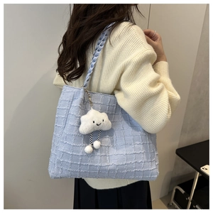 Detail of light blue tweed tote bag with cute cloud plush charm and woven strap