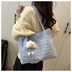 Light blue woven tote bag with braided handle and white cloud charm shown on model