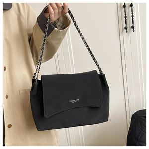 Detail of silver chain strap and silver logo on minimalist black matte tote bag