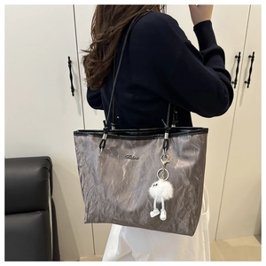 Détail du sac cabas gris plissé avec bandoulières noires et pendentif peluche blanc