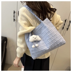Close-up of light blue tote bag with 3D grid texture and a cute cloud pendant on model