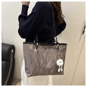 Détail du sac cabas argenté métallisé avec texture plissée et breloque monstre en peluche