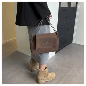 Detailed view of dark brown leather shoulder bag with chain strap on model