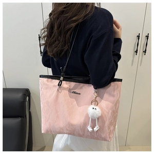 Sac fourre-tout rose avec lanières noires et peluche porté par un mannequin femme