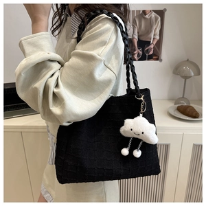Détail d'un sac cabas noir avec tissu texturé et pendentif nuage en peluche doux
