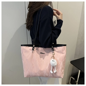 Détail d'un cabas rose plissé avec bandoulière noire et charm peluche porté par un mannequin
