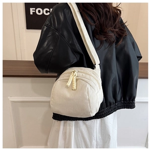 Detail of white corduroy crossbody bag texture with braided rope zipper pullers