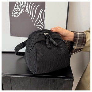 Detail of black corduroy shell bag showing dual zippers and braided rope pulls