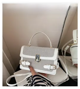 Detail of white patchwork handbag featuring contrast textures and gold buckle closure