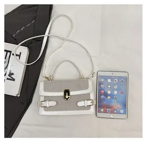 Detail of color-block flap bag showing cream fabric texture and metal twist lock