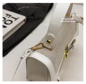 Close-up of golden metal buckle and detachable shoulder strap on white crossbody bag