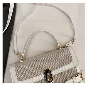 Close-up of contrast grid texture on light beige shoulder bag with gold metal buckle