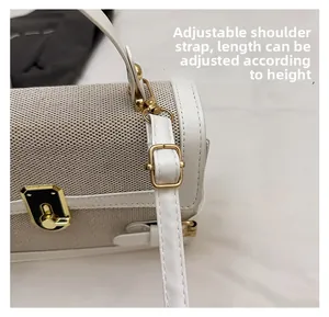 Detail view of adjustable shoulder strap with gold metal buckle on white leather bag