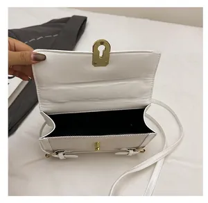 Detail view of the white crossbody bag interior with simple design and gold keyhole lock
