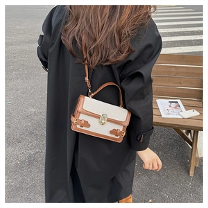 Detail of a vintage-style canvas and leather crossbody bag featuring a metal twist lock