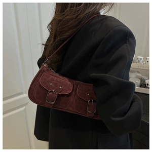 Gros plan sur un sac baguette bordeaux vintage en daim avec deux poches et boucles métal