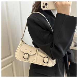 Détail du sac baguette crème avec deux poches avant et boucles métalliques sur le mannequin