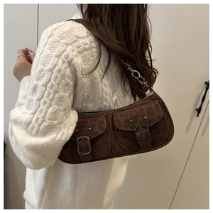 Détail du sac baguette en daim marron vintage avec doubles poches à boucle sur l'épaule