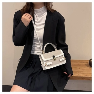 Detail of white leather and beige linen patchwork handbag with golden metal lock and strap