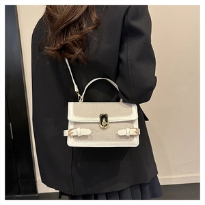 Close-up of contrast leather crossbody bag on black blazer showing strap and metal lock